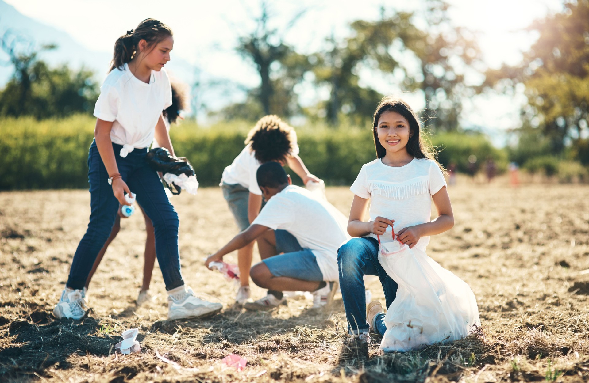 Shot of a group of teenagers picking up litter off a field at summer camp